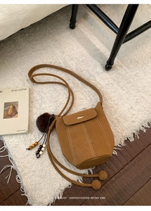 Detail of retro brown bucket bag with contrast stitching and decorative plush charm