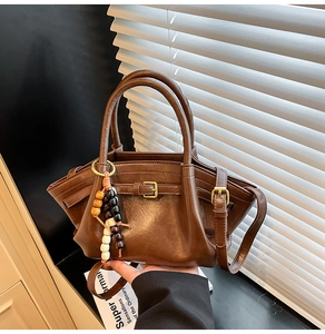 Detail of a brown textured faux leather handbag with colorful beads and buckled straps