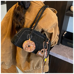 Close-up of black suede Boston bag with donut charm and heart-shaped mini pouch accessory