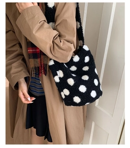 Détail d'un sac seau en peluche à pois noirs et blancs avec étiquette de marque latérale