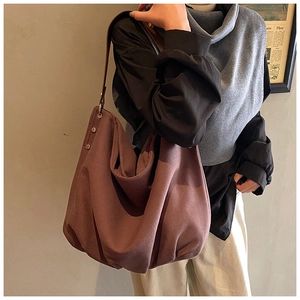 Detail view of large mauve canvas tote bag with brown leather strap and rivet accents