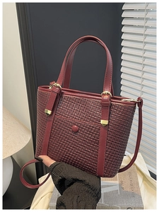 Dettaglio borsa tote intrecciata rosso intenso con manico in pelle e finiture in oro