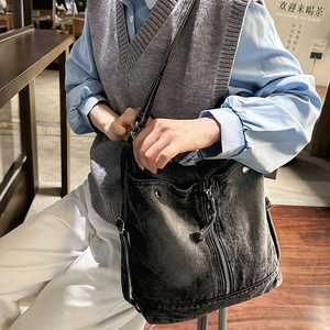 Detail view of washed black denim crossbody bag with metal snaps and zipper accents