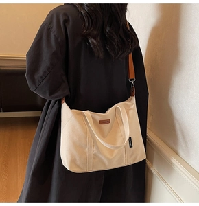 Detail view of a beige canvas tote bag with brown detachable strap for daily commuting