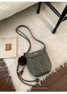 Close-up of retro bucket bag with white contrast stitching and golden buckle detail