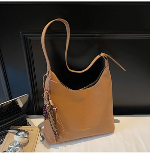 Close-up of brown leather hobo bag with gold embossed logo and decorative tassel