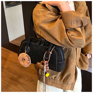 Detail of matte black shoulder bag with white contrast stitching and cute charms
