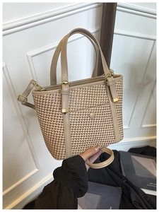 Dettaglio di una borsa tote in paglia bicolore con finiture in pelle marrone e fibbie