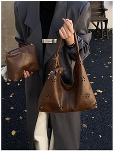 Détail des fleurs découpées au laser sur un sac cabas en cuir marron vintage avec pochette