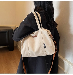 Minimalist canvas tote bag with brown straps shown on shoulder in a lifestyle setting