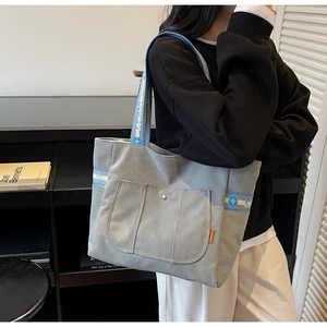 Detail view of canvas tote bag with metal snap pocket and jacquard woven strap