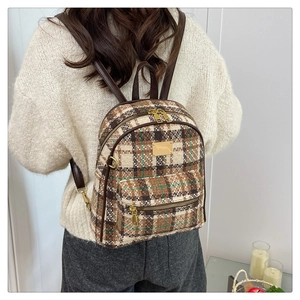 Détail du sac à dos vintage à carreaux sur pull en maille beige avec boucles en métal