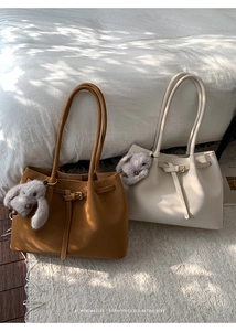 Close-up of minimalist retro tote bags in brown and white with plush bunny charms