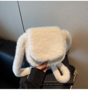 Detail of soft white faux fur crossbody bag featuring a plush texture and flap design