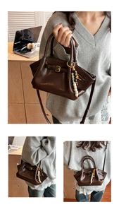 Detail of dark brown leather tote with a colorful beaded charm and gold hardware accents