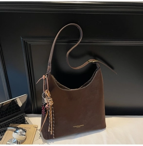Detail of dark brown hobo bag with contrast stitching and branded leather gold logo