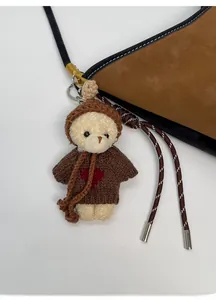 Dettaglio del ciondolo a forma di orsetto con maglione a cuore su una borsa a secchiello