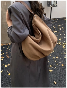 Close-up of a brown oversized tote bag with silver metal rings and leather straps