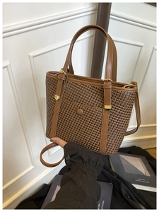 Dettaglio borsa tote intrecciata marrone con cinturini in pelle e finiture dorate