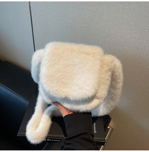 Close-up of white faux fur shoulder bag with soft plush texture and wide fuzzy handle