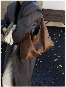 Détail d'un cabas marron ajouré porté avec un manteau gris au style rétro chic