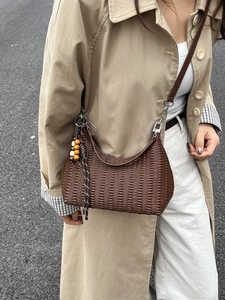 Vintage dark brown textured crescent shoulder bag with wood bead charm on beige coat