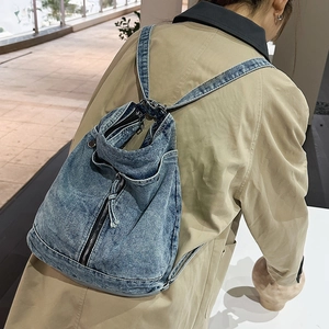 Detail of vintage blue denim backpack with zipper accents and drawstring closure