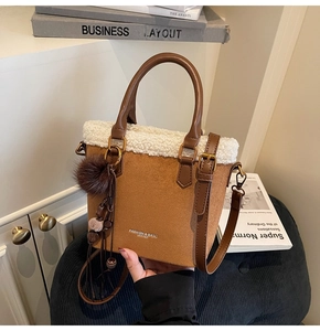 Détail du sac seau en daim avec bordure en peau lainée et pendentif à pompon décoratif