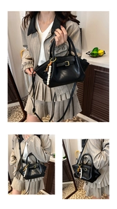 Detail view of a black leather handbag with decorative buckles and wooden bead pendant