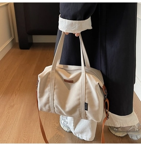 Close-up of canvas tote bag with brown leather trim and TAOCAITU brand logo patch