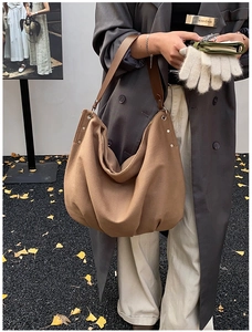 Close-up of large canvas hobo bag with dark brown leather strap and rivet details