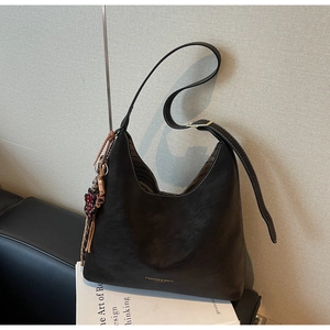 Detail of black hobo bag with contrast stitching and decorative floral tassel pendant