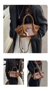 Close-up of brown vintage leather handbag featuring buckle straps and ethnic beaded pendant