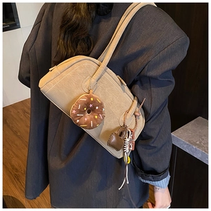 Detail of khaki baguette bag featuring a plush donut charm and stylish leather accents