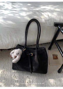Détail du sac cabas minimaliste en daim noir avec boucle en métal et breloque lapin en peluche