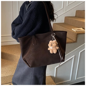 Macro view of deep brown tote bag with matte texture and cute plush bear charm