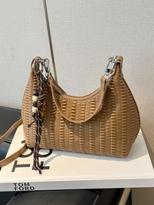 Vintage khaki pleated shoulder bag with wooden bead charm on a minimalist white book