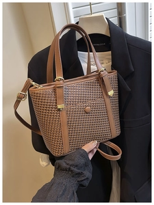 Dettaglio borsa tote marrone intrecciata con manici in pelle e finiture in metallo dorato