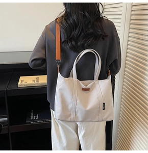 Detail of grey canvas tote with wide orange adjustable shoulder strap for crossbody use