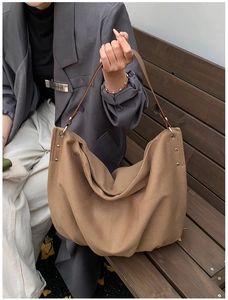 Detail of hobo tote bag with silver rivets and leather strap on wooden background