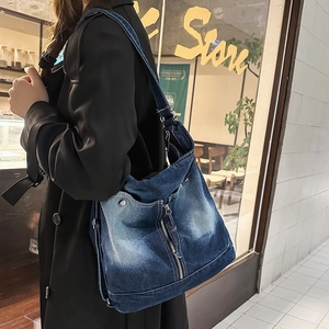 Detail of vintage blue denim crossbody bag featuring retro washed texture and metal rivets