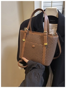 Dettaglio della borsa tote intrecciata marrone con finiture in pelle e fibbie dorate