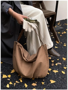 Detailed close-up of brown canvas tote bag with leather strap and metal rivet accents