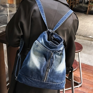 Detail of vintage blue denim backpack showing washed texture and metal zipper accents
