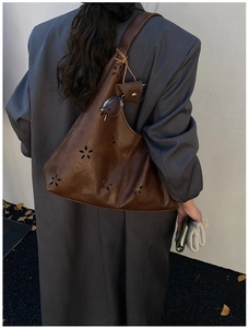 Détail du sac hobo en cuir marron avec motifs ajourés et mini pochette à lunettes suspendue