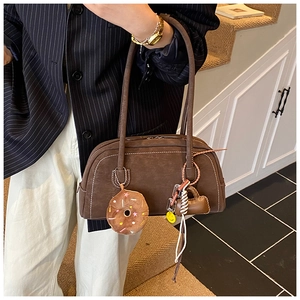 Detail of brown matte shoulder bag with white contrast stitching and cute charms