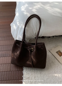 Detail view of deep coffee tote bag with matte texture and decorative gold buckle