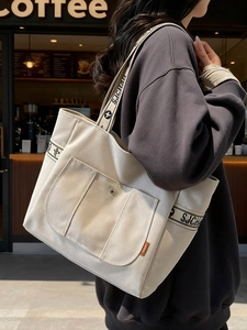 Minimalist beige canvas tote bag with lettered straps and large snap button pocket