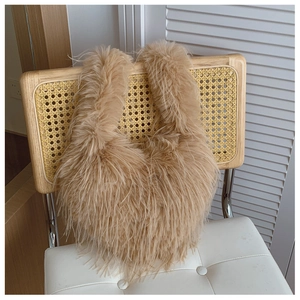Détail d'un sac à bandoulière en fausse fourrure marron chameau suspendu à une chaise