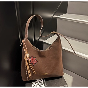 Macro shot of brown suede hobo bag with tassel charms and golden leather text details